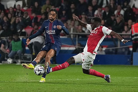 Monaco's Jordan Teze, right, tries block a shot by PSG's Bradley Barcola during the French League One soccer match between Paris Saint-Germain and Monaco in Paris.