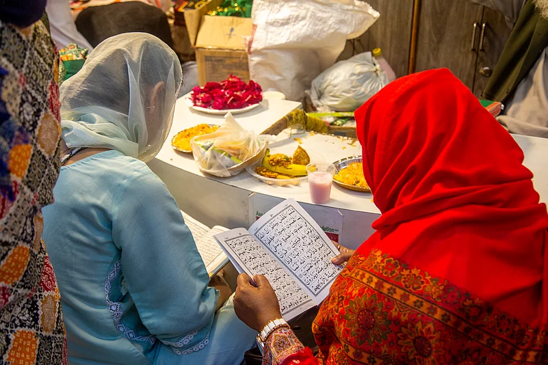 Two women read while waiting to break their fast at Nizamuddin Dargah during Ramadan.