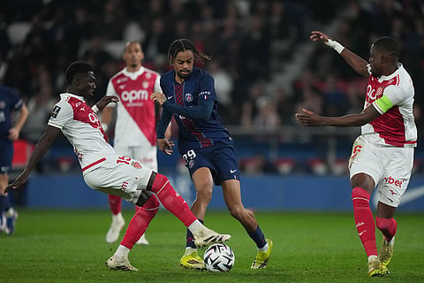 Monaco's Lamine Camara, left, and PSG's Bradley Barcola, center, compete for the ball during the French League One soccer match between Paris Saint-Germain and Monaco in Paris.