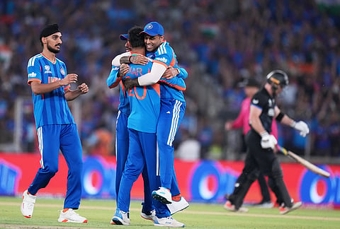 India's captain Suryakumar Yadav, center facing the camera, hugs teammate Axar Patel for taking the wicket of New Zealand's Glenn Phillips, right, during the T20 World Cup cricket final match between India and New Zealand in Ahmedabad.