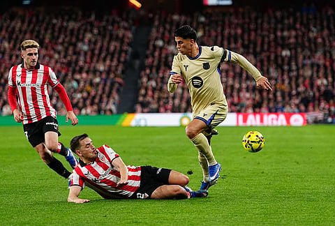Athletic Bilbao's Andoni Gorosabel, bottom, challenges Barcelona's Joao Cancelo, right, during the Spanish La Liga soccer match between Athletic Bilbao and Barcelona in Bilbao, Spain.