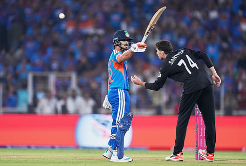 India's Ishan Kishan celebrates his fifty runs as New Zealand's captain Mitchel Santner, right, collects the ball during the T20 World Cup cricket final match between India and New Zealand in Ahmedabad.