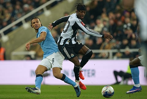 Manchester City's Nathan Ake, left, and Newcastle's Anthony Elanga fight for the ball during the fifth round FA Cup soccer match between Newcastle and Manchester City in Newcastle, England.