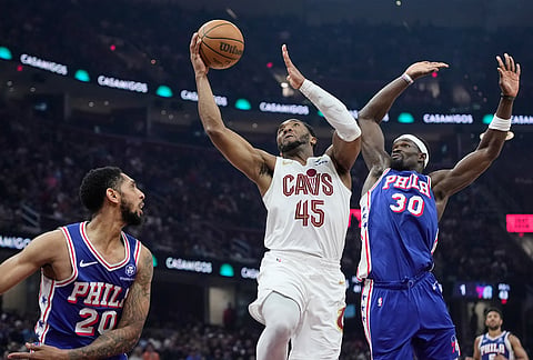 Cleveland Cavaliers guard Donovan Mitchell (45) shoots between Philadelphia 76ers guard Cameron Payne (20) and center Adem Bona (30) in the first half of an NBA basketball game in Cleveland.