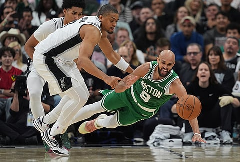 Boston Celtics guard Derrick White (9) dives past San Antonio Spurs forward Keldon Johnson (3) for a loose ball during the second half of an NBA basketball game in San Antonio.