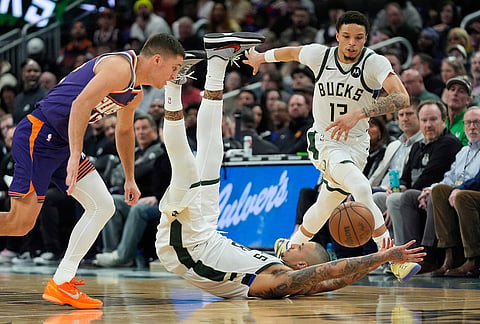 Milwaukee Bucks' Kyle Kuzma, middle, loses control of the ball between Ryan Rollins, right, and Phoenix Suns' Collin Gillespie, left, during the second half of an NBA basketball game in Milwaukee.