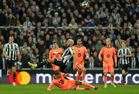 Newcastle's Joelinton, top, and Barcelona's Raphinha battle for the ball during the Champions League round of 16 first leg soccer match between Newcastle United and Barcelona in Newcastle, England.