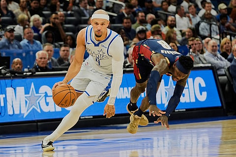 Cleveland Cavaliers guard Dennis Schroder, right, gets tripped up as Orlando Magic guard Jalen Suggs, left, drives past him during the first half of an NBA basketball game in Orlando, Fla.