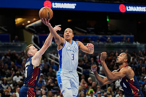 Orlando Magic guard Desmond Bane (3) makes a shot as he gets between Cleveland Cavaliers guard Sam Merrill, left, and center Evan Mobley during the first half of an NBA basketball game in Orlando, Fla.