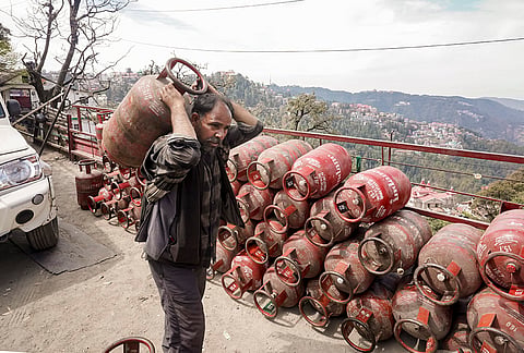 A worker carries an LPG cylinder near a distribution centre, amid supply crisis in the country, in Shimla.