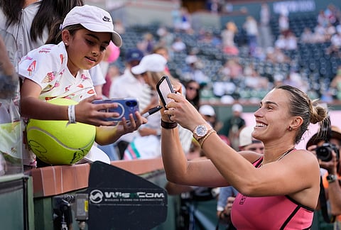 Aryna Sabalenka, of Belarus, right, smiles while signing autographs for fans after defeating Linda Noskova, of the Czech Republic, during a semifinal match at the BNP Paribas Open tennis tournament in Indian Wells California.