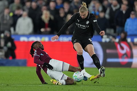 West Ham's Aaron Wan-Bissaka, bottom, tackles Manchester City's Erling Haaland during the English Premier League soccer match between West Ham United and Manchester City in London, England.