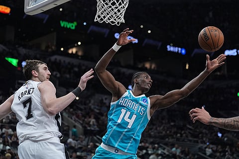 Charlotte Hornets forward Moussa Diabate (14) reaches past San Antonio Spurs center Luke Kornet (7) for a rebound during the second half of an NBA basketball game in San Antonio.
