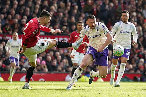 Manchester United's Diogo Dalot clears the ball in front of Aston Villa's John McGinn during the Premier League soccer match between Manchester United and Aston Villa in Manchester, England.
