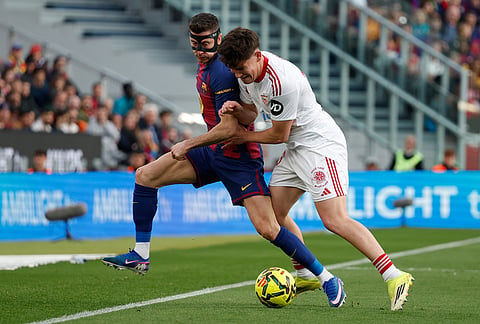 Barcelona's Robert Lewandowski, left, challenges for the ball with Sevilla's Oso during the Spanish La Liga soccer match between Barcelona and Sevilla in Barcelona, Spain.