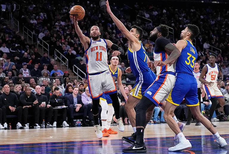 New York Knicks' Jalen Brunson (11), left, drives to the basket past Golden State Warriors defenders during the second half of an NBA basketball game in New York. - | Photo: AP/Seth Wenig