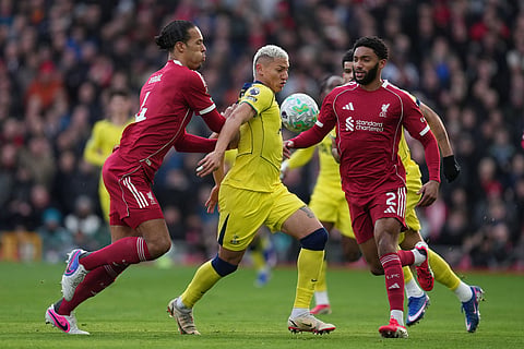 Liverpool's Virgil van Dijk, left, and Tottenham's Richarlison fight for the ball during the Premier League soccer match between Liverpool and Tottenham in Liverpool, England.