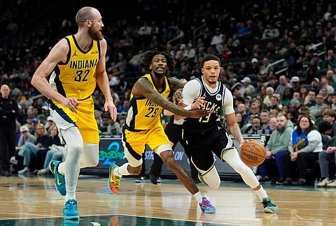 Milwaukee Bucks' Ryan Rollins (13) drives to the basket against Indiana Pacers' Quenton Jackson (29) and Jay Huff (32) during the second half of an NBA basketball game in Milwaukee.
