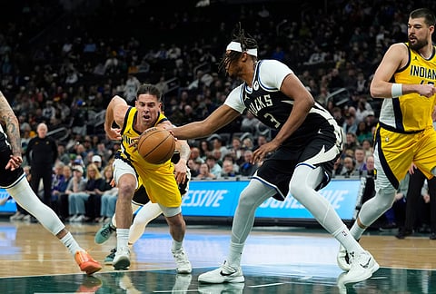 Indiana Pacers' T.J. McConnell, left, drives to the basket against Milwaukee Bucks' Myles Turner during the first half of an NBA basketball game, in Milwaukee.