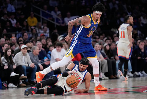 Golden State Warriors' Gui Santos, top, fouls New York Knicks' Josh Hart during the first half of an NBA basketball game in New York.