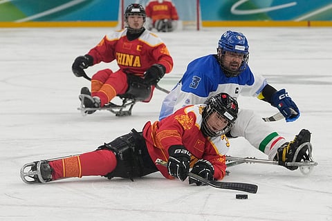 Chine's Li Hongguan challenges for the puck with Italy's Gianluigi Rosa during the Group A hockey match between Italy and China at the 2026 Winter Paralympics, in Milan, Italy.