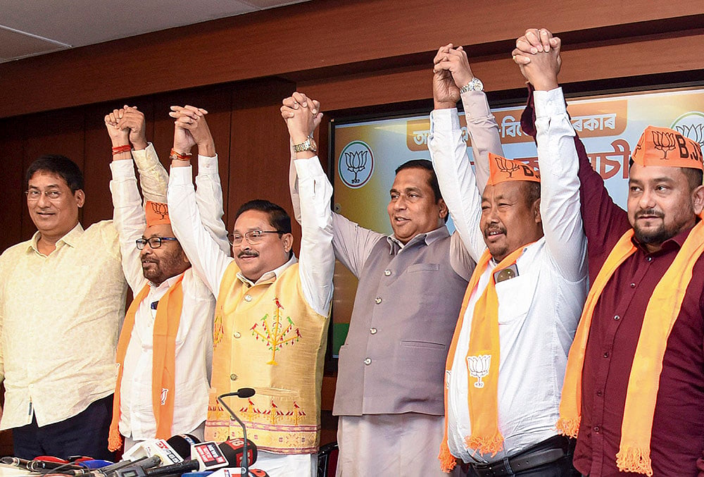 | Photo: PTI  : Assam BJP President Dilip Saikia joins hands with newly joined party leader Bhupen Roy and other leaders during a press conference, in Guwahati.
