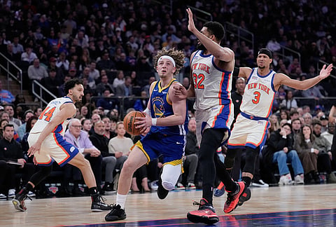 Golden State Warriors' Brandin Podziemski, second from left, drives to the basket through New York Knicks defenders during the first half of an NBA basketball game in New York. 