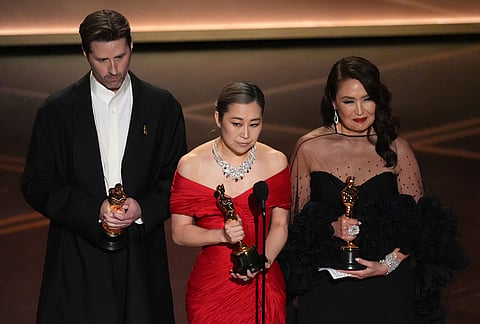 Chris Appelhans, from left, Maggie Kang, and Michelle L.M. Wong accept the award for animated feature film for "K-pop Demon Hunters" during the Oscars at the Dolby Theatre in Los Angeles.