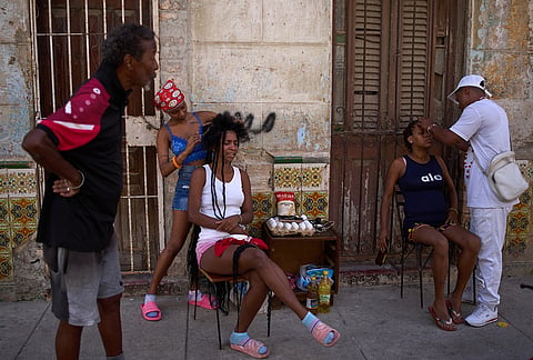 Hairdressers style the hair of their clients in the open air during a blackout in Havana, Cuba, Thursday, March 5, 2026. 