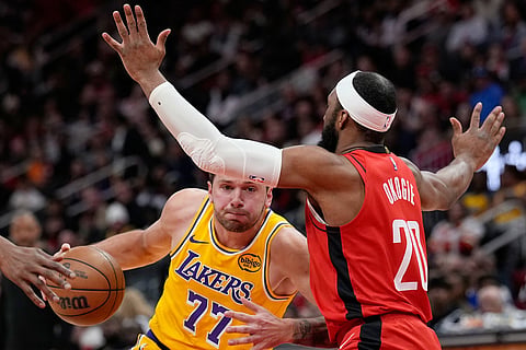 Los Angeles Lakers' Luka Doncic (77) drives toward the basket as Houston Rockets' Josh Okogie (20) defends during the first half of an NBA basketball game in Houston.