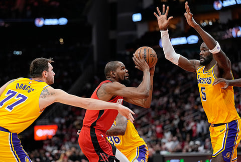 Houston Rockets' Kevin Durant, center shoots as Los Angeles Lakers' Luka Doncic (77) and Deandre Ayton (5) defend during the second half of an NBA basketball game in Houston. 