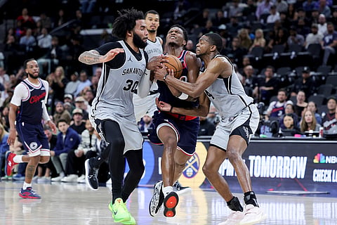 Los Angeles Clippers guard Bennedict Mathurin, center, drives against San Antonio Spurs forward Julian Champagnie, left, and guard De'Aaron Fox during the second half of an NBA basketball in Inglewood, Calif.