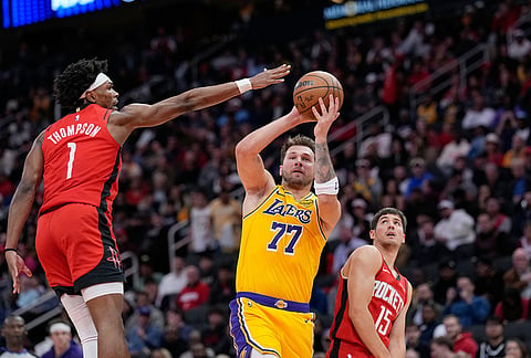 Los Angeles Lakers' Luka Doncic (77) shoots as Houston Rockets' Amen Thompson (1) defends during the first half of an NBA basketball game in Houston.