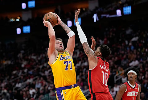 Los Angeles Lakers' Luka Doncic (77) shoots as Houston Rockets' Jabari Smith Jr. (10) defends during the first half of an NBA basketball game in Houston. 