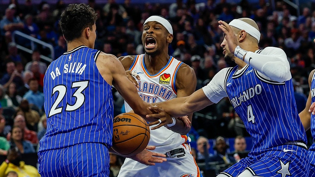 AP : Oklahoma City Thunder guard Shai Gilgeous-Alexander, centre, has ball stripped away by Orlando Magic forward Tristan da Silva (23) and guard Jalen Suggs (4) during the second half of their NBA basketball game.