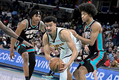 Denver Nuggets forward Spencer Jones (21) handles the ball between Memphis Grizzlies forwards Jaylen Wells, right, and GG Jackson II (45) in the second half of an NBA basketball game in Memphis, Tennessee.