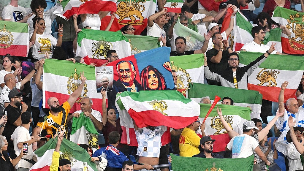 Iran supporters wave flags and hold images of Reza Pahlavi, the son of the last Shah of Iran, during the Women's Asian Cup match between Iran and the Philippines in Robina. - AP