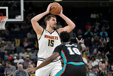 Denver Nuggets center Nikola Jokic (15) handles the ball against Memphis Grizzlies forward Olivier-Maxence Prosper (18) in the first half of an NBA basketball game in Memphis, Tennessee.