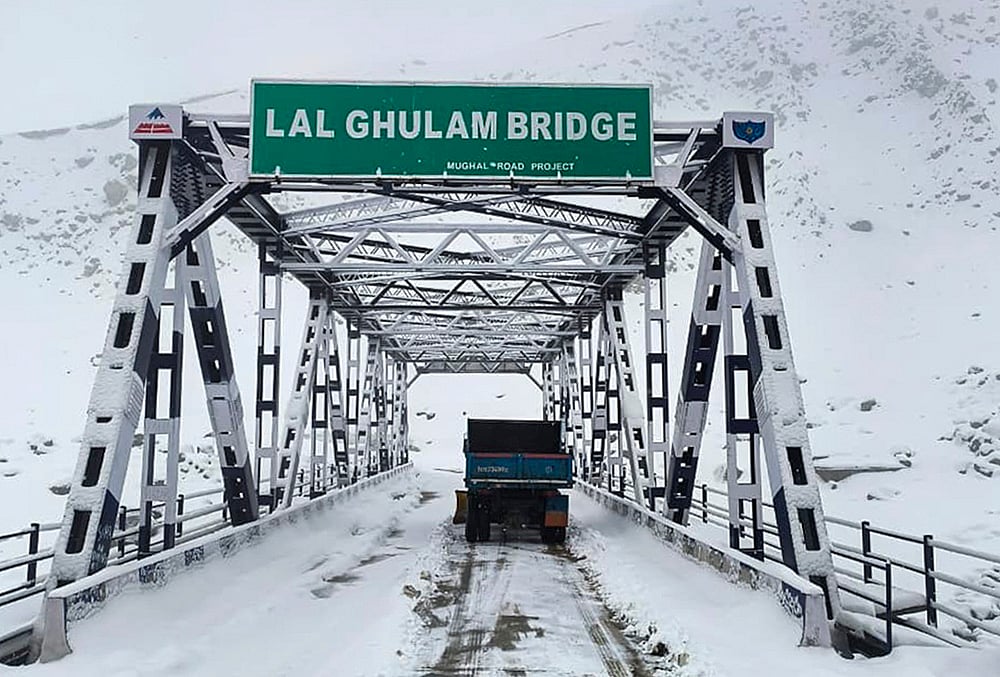 A vehicle passes through the snow-covered Lal Ghulam Bridge following fresh snowfall, in Rajouri, Jammu and Kashmir. - | Photo: PTI