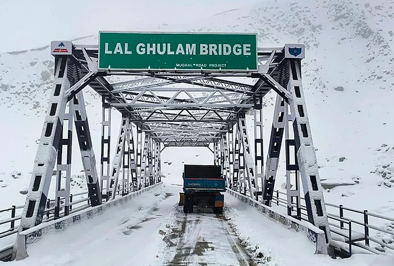 A vehicle passes through the snow-covered Lal Ghulam Bridge following fresh snowfall, in Rajouri, Jammu and Kashmir. - | Photo: PTI