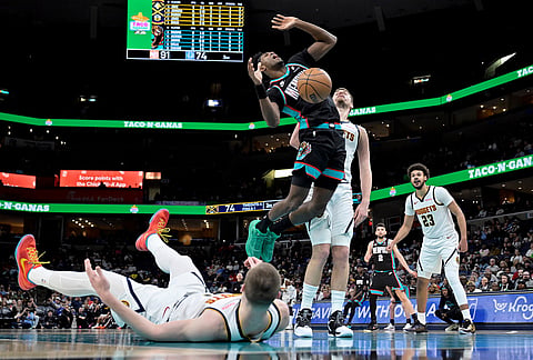 Memphis Grizzlies forward Olivier-Maxence Prosper, left center, shoots against Denver Nuggets center Nikola Jokic, center right, in the second half of an NBA basketball game in Memphis, Tennessee.