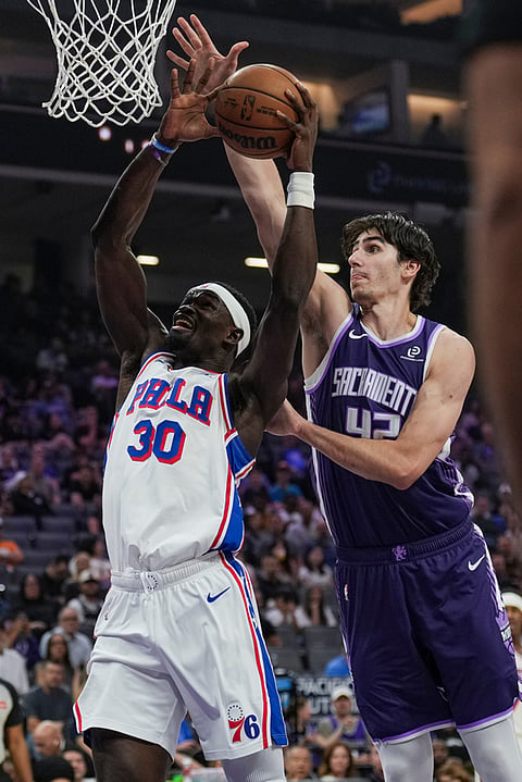 Philadelphia 76ers center Adem Bona (30) is fouled by Sacramento Kings center Maxime Raynaud during the first half of an NBA basketball game, in Sacramento, California. 