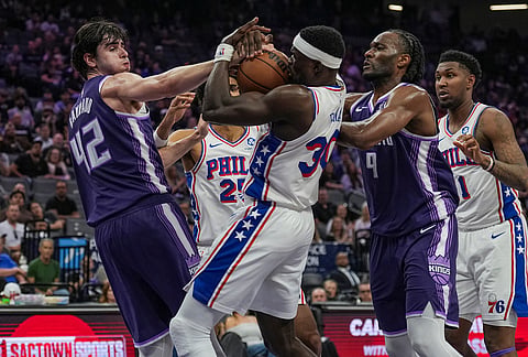 Sacramento Kings center Maxime Raynaud (42), forward Precious Achiuwa (9) and Philadelphia 76ers center Adem Bona (30) fight for the rebound during the first half of an NBA basketball game, in Sacramento, California.