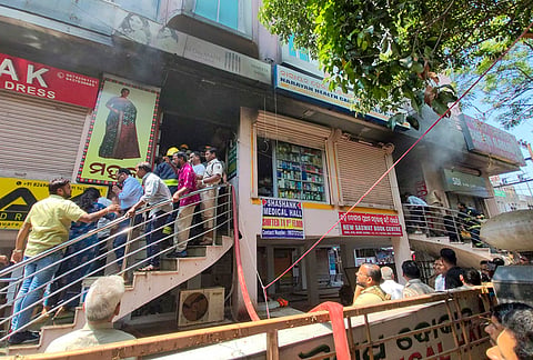 People gather after a fire broke out at a shop at Mahavir Market Complex near CRP Square, in Bhubaneswar.
