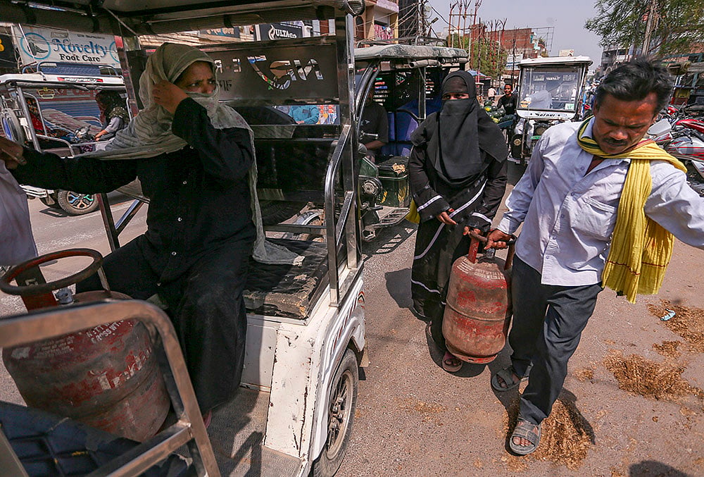 People carry LPG cooking gas cylinders, in Prayagraj