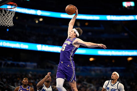 Los Angeles Lakers guard Austin Reaves (15) goes up to dunk between Orlando Magic forward Jamal Cain, second from left, and guard Jalen Suggs, right, during the first half of an NBA basketball game in Orlando, Fla.