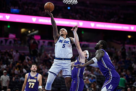 Orlando Magic forward Paolo Banchero (5) goes up to shoot as Los Angeles Lakers guard Austin Reaves, second from right, defends and Lakers guard Luka Doncic (77) and center Deandre Ayton, right, watch during the second half of an NBA basketball game in Orlando, Fla.