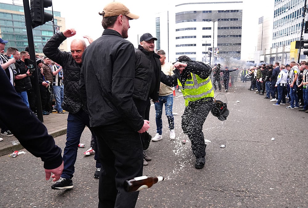 | Photo: Owen Humphreys/PA via AP : A police officer reacts as a bottle is thrown during clashes between Sunderland and Newcastle United fans before the Premier League match between Newcastle and Sunderland outside St James' Park, Newcastle upon Tyne, England.