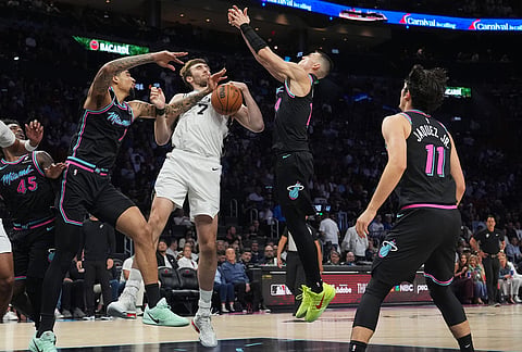 San Antonio Spurs center Luke Kornet (7) fights for control of the ball against Miami Heat center Kel'el Ware, left, and guard Tyler Herro, second from right, during the first half of an NBA basketball game, in Miami.