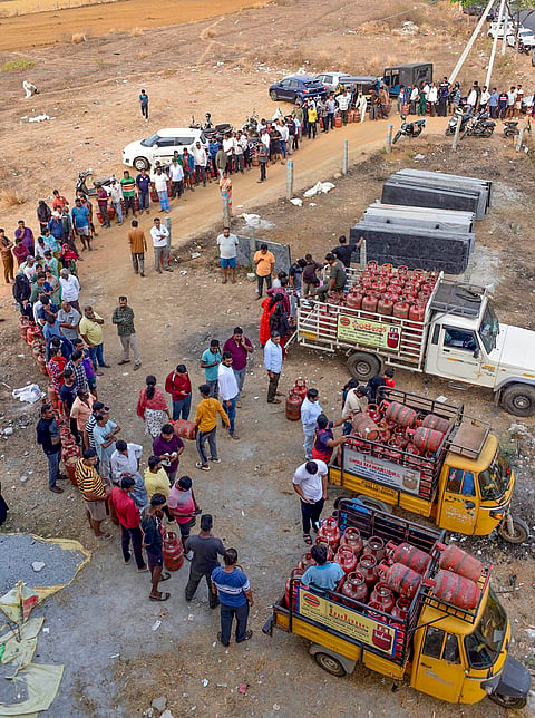 People wait in a queue with empty LPG cooking gas cylinders to avail refilled ones amid ongoing supply crisis, in Chikkamagaluru.